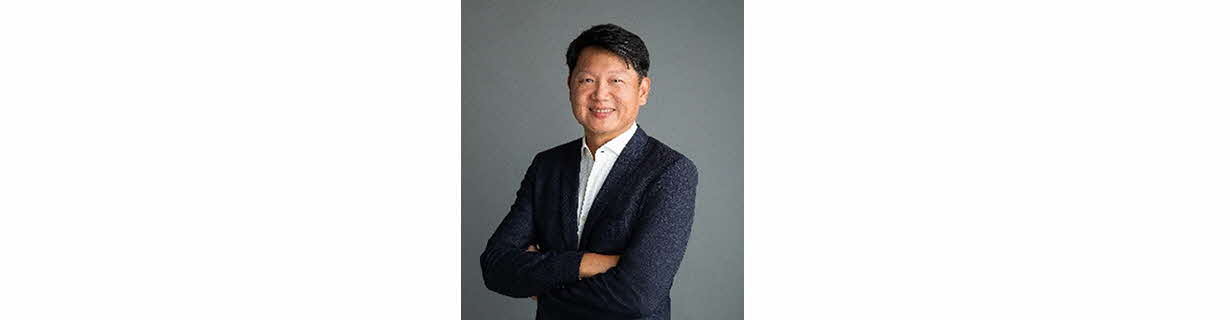 Portrait of Danny Yong, man in a suit, arms folded and smiling